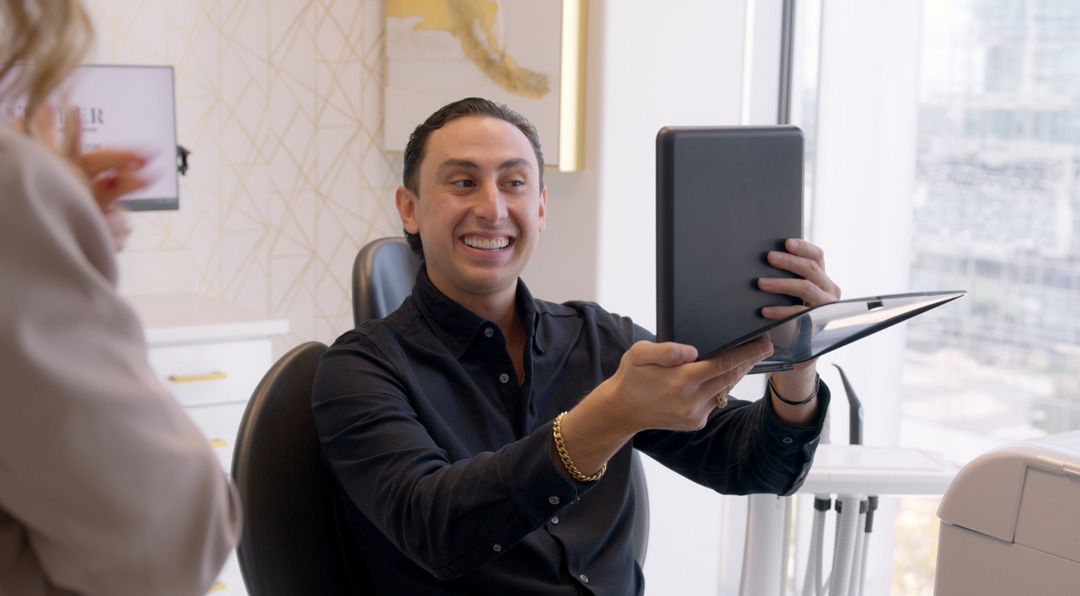 Happy Patient looking at new Veneers in the Mirror